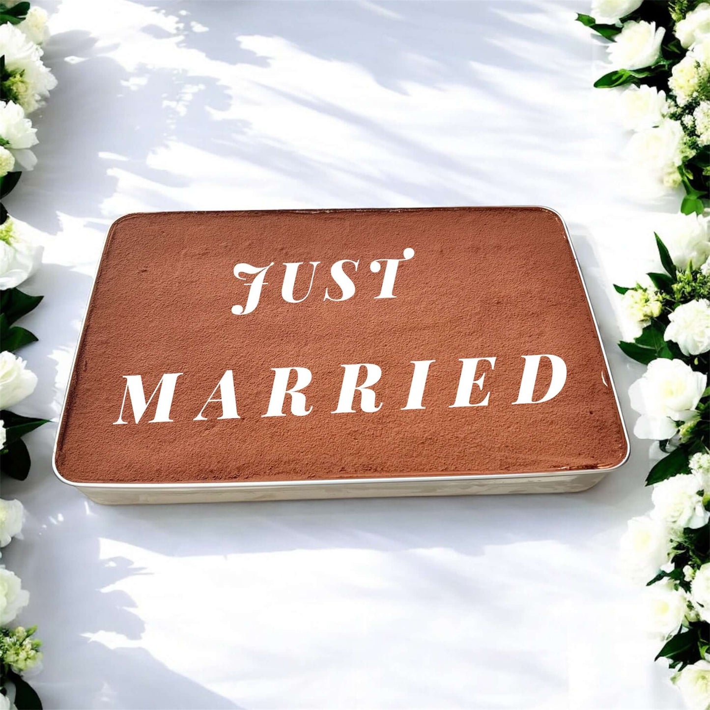 Tiramisu Wedding Cake Tray with 'Just Married' written on top, surrounded by white flowers for wedding celebration.