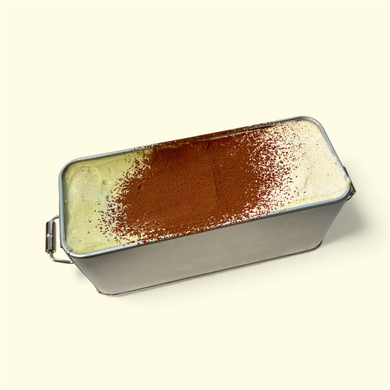 Tiramisu Duo Box 310g featuring classic and pistachio tiramisu topped with cocoa powder in a metal container.