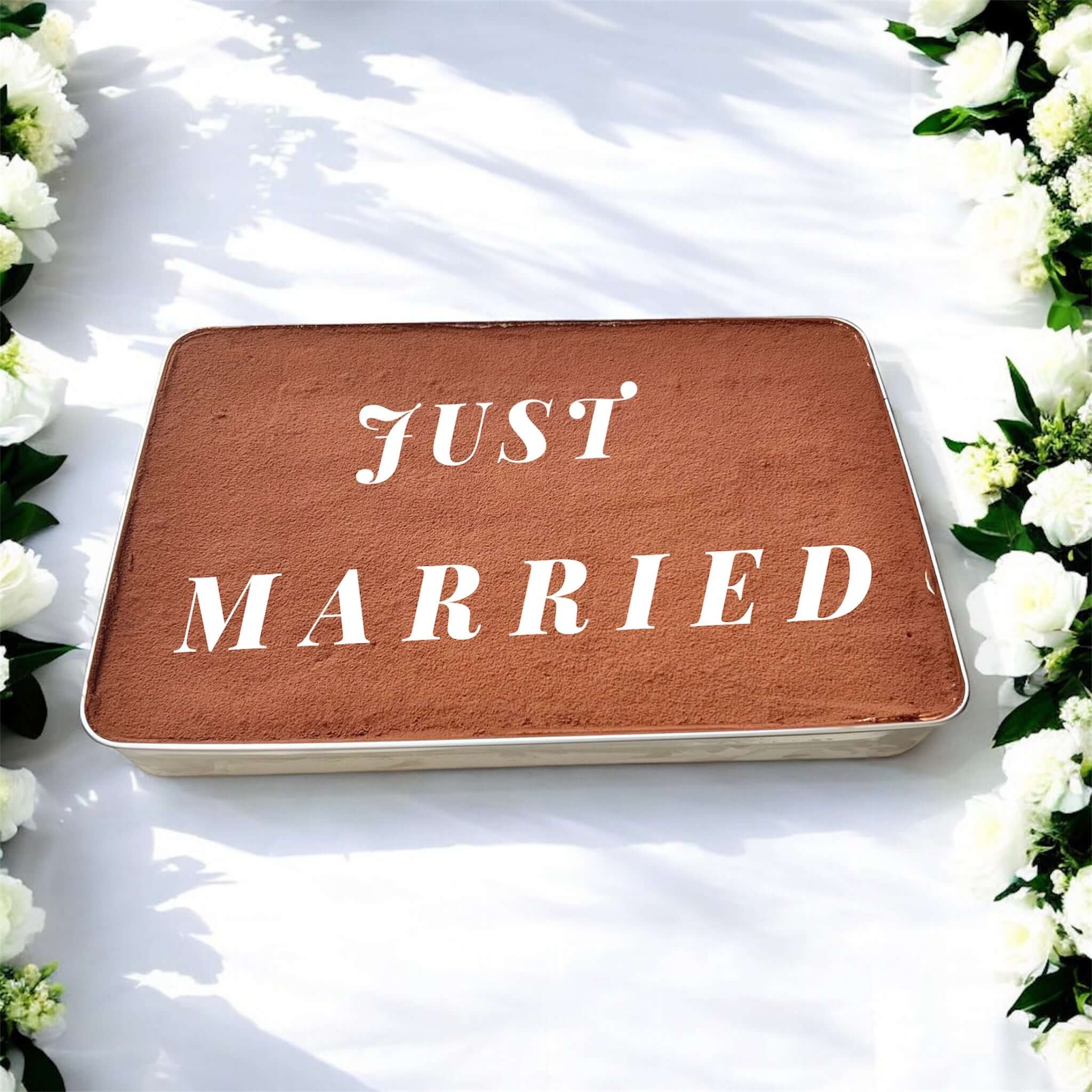Tiramisu Wedding Cake Tray with 'Just Married' written on top, surrounded by white flowers for wedding celebration.