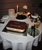 Tiramisu Wedding Cake on a table decorated for an intimate event with a candle and other desserts.