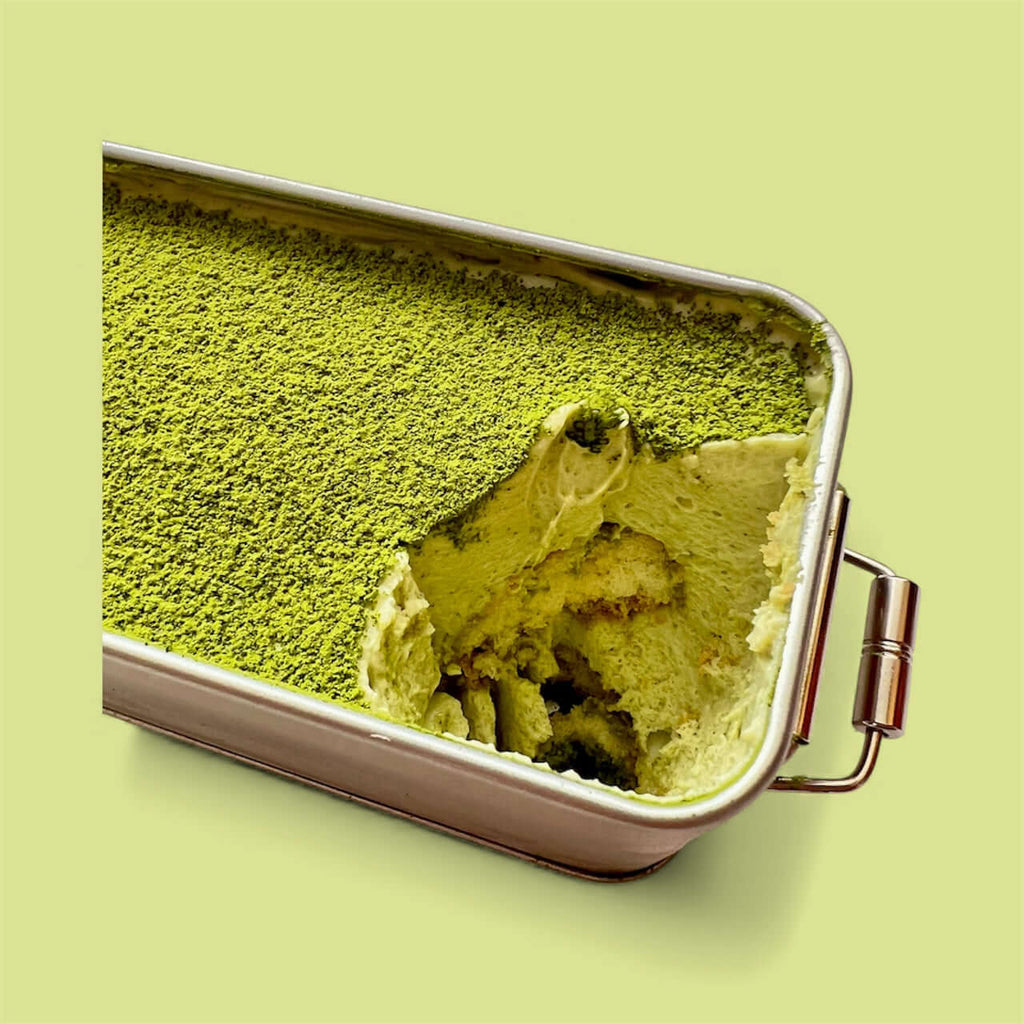 Close-up of Pistachio Matcha Tiramisu with one serving taken, showcasing vibrant green layers.