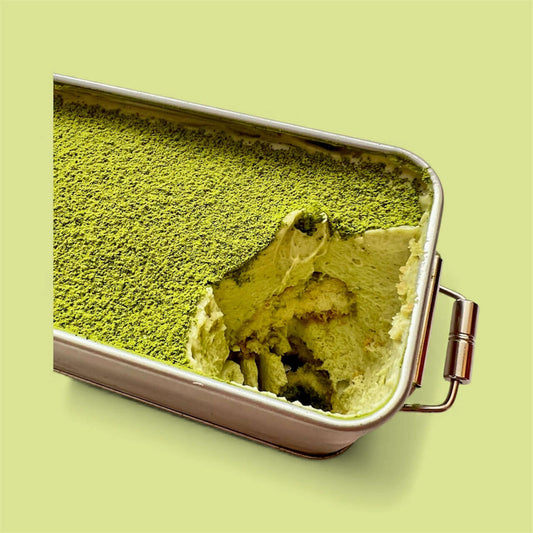 Close-up of Pistachio Matcha Tiramisu with one serving taken, showcasing vibrant green layers.